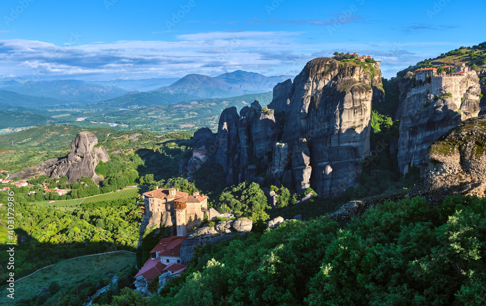 Morning view of Moni Agias Varvaras Roussanou in morning, Meteora, Greece and Varlaam monastery, rocks and valley. Rich foliage. UNESCO World Heritage