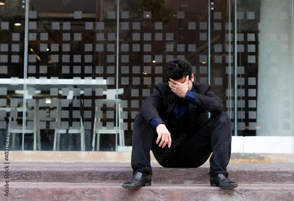 Unemployed tired or stressed businessman sitting on the walkway Unemployed tired or stressed businessman sitting on the walkway