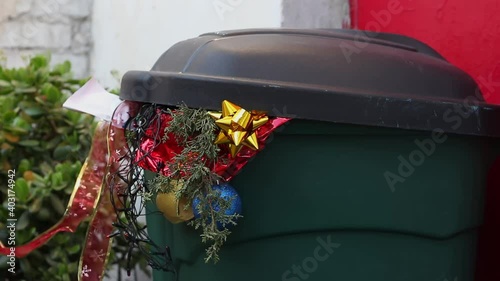 Christmas waste in a dumpster. Pollution of the environment. The Environmental Cost of Christmas Pollution. Wrapping paper, Christmas tree lights, Christmas decorations, holiday cards, tin foil