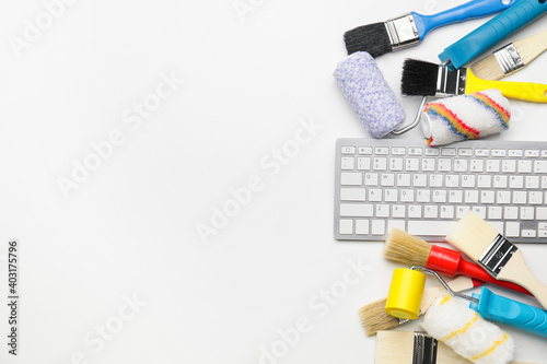 Computer keyboard and painting tools on white background