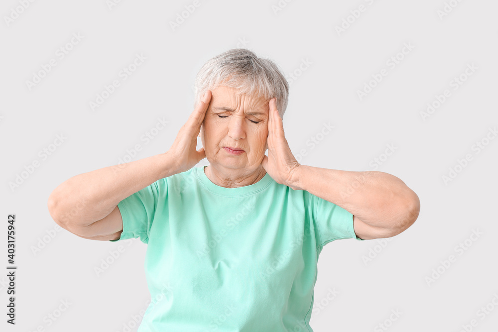 Stressed senior woman suffering from headache on light background Stressed senior woman suffering from headache on light background