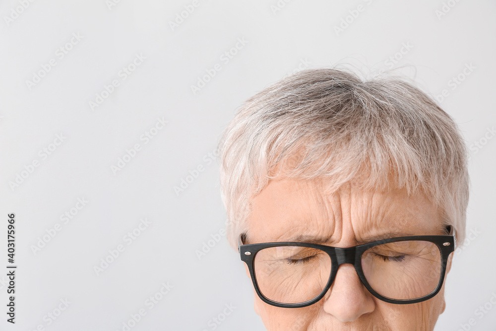 Stressed senior woman on light background