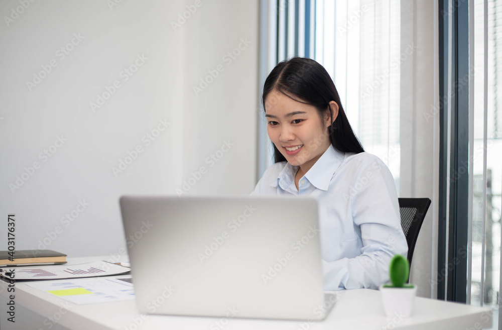An Asian woman looks good and is pretty working on a laptop Business women are busy working with laptop computers in the office An Asian woman looks good and is pretty working on a laptop Business women are busy working with laptop computers in the office