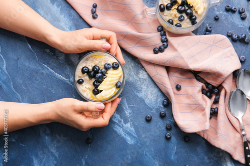 Female hands with tasty oatmeal and blueberry in bowl on table