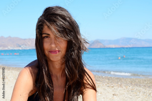 Young Woman Sitting on the Beach on a Sea Background 