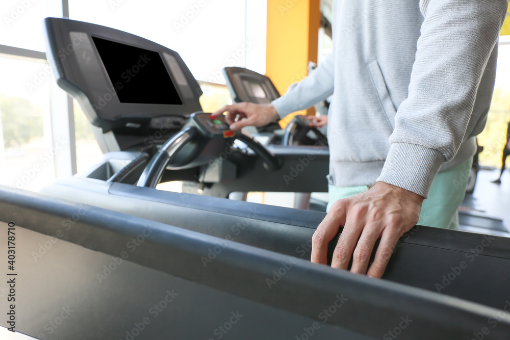 Young man training on treadmill in gym, closeup Young man training on treadmill in gym, closeup