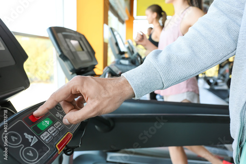 Young man training on treadmill in gym, closeup