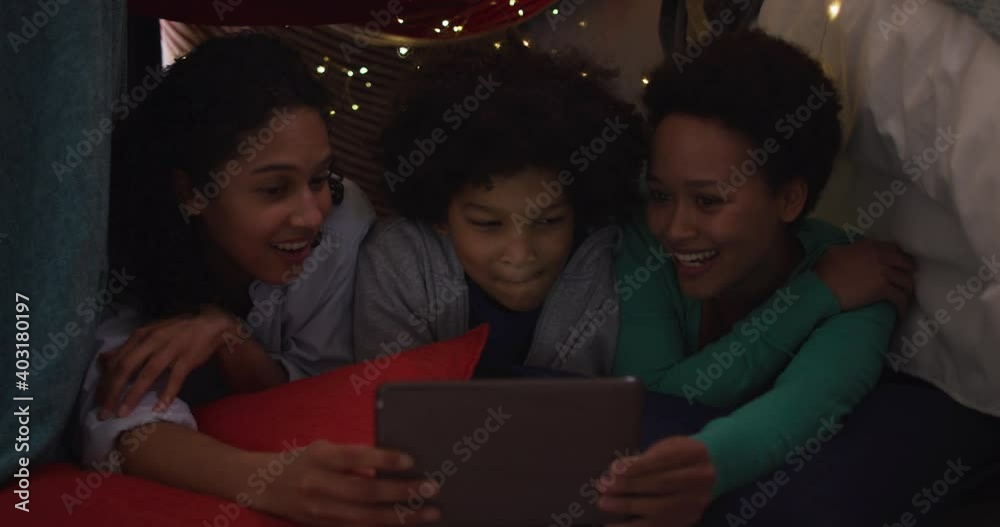 Mixed race lesbian couple and daughter using tablet lying in bedroom camp Mixed race lesbian couple and daughter using tablet lying in bedroom camp