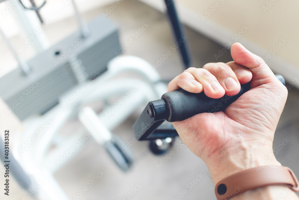 Close up of man's hand pull cable weight in a fitness gym.