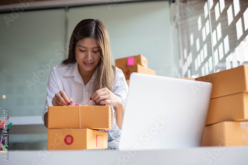 An Asian owner holds a package in a brown box, ready for delivery to a customer who orders online. As he sat in the home office