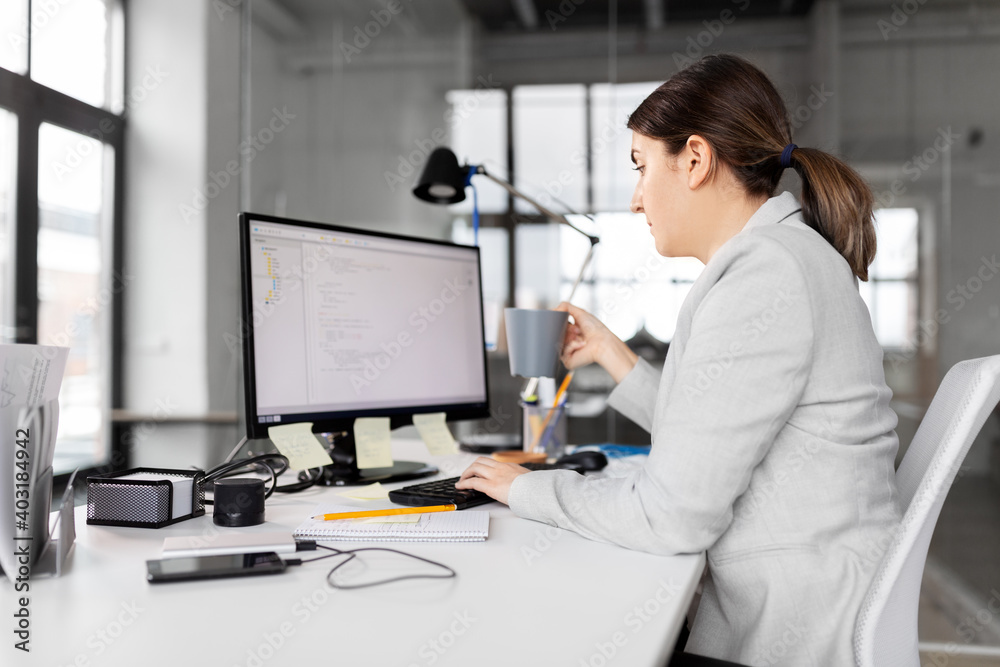 business, startup and people concept - businesswoman with computer and coffee working at office business, startup and people concept - businesswoman with computer and coffee working at office