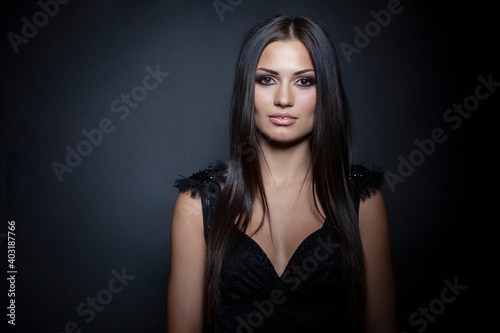 Beauty front portrait. Beautiful sensual young woman with long straight hair and bright makeup, over black background.