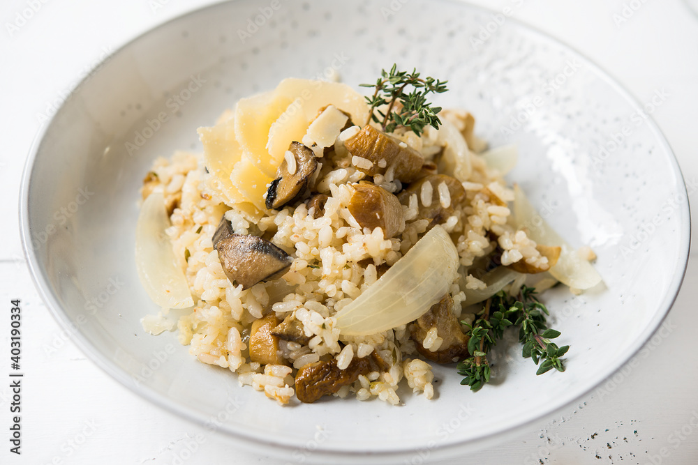 Risotto with porcini mushrooms and parmesan on a light background, selective focus