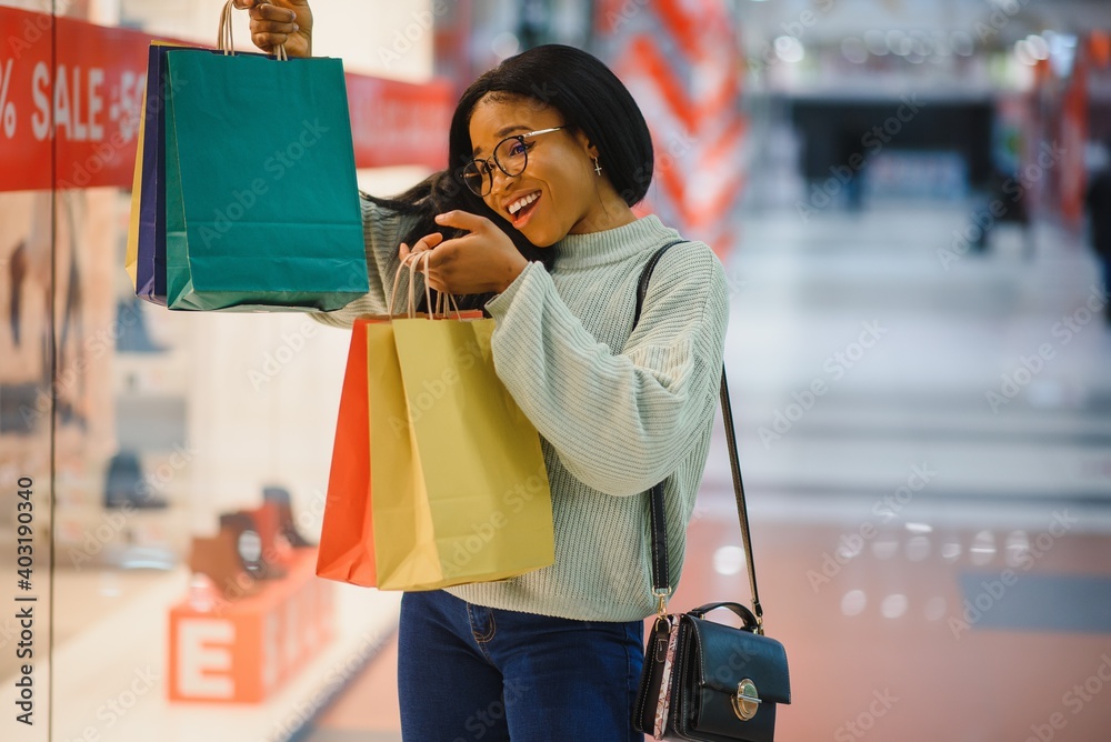 young African American woman at shopping mall in new normal after covid-19 - happy and beautiful black girl in face mask holding shopping bags enjoying at beauty fashion store young African American woman at shopping mall in new normal after covid-19 - happy and beautiful black girl in face mask holding shopping bags enjoying at beauty fashion store