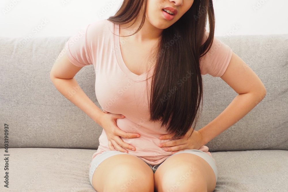 Woman using her hands touching her tummy Feeling painful after eating something unhygienic or during her menstrual period Women health and medical treatment concept Woman using her hands touching her tummy Feeling painful after eating something unhygienic or during her menstrual period Women health and medical treatment concept