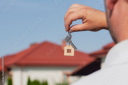 Man holds the keys to the house in his hands against the backdrop of residential buildings. Concept for buying and renting apartments.