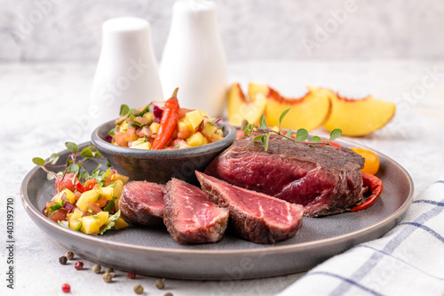 Fried beef steak with peach fruit salsa, tomato and chili.