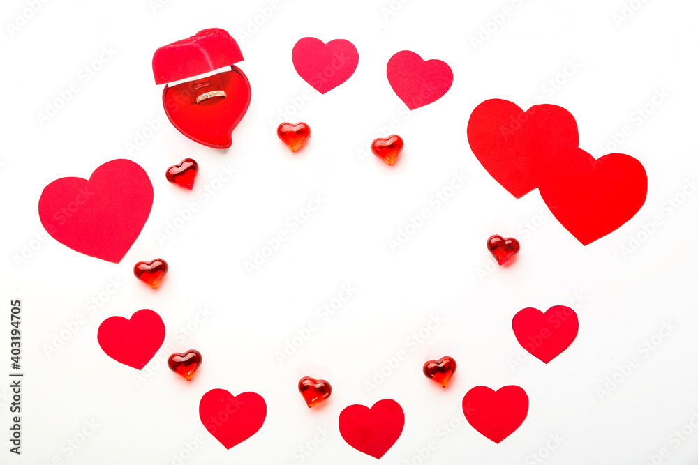 Red hearts of different sizes for Valentine's day and glass hearts and a velvet box with a heart ring on a white background