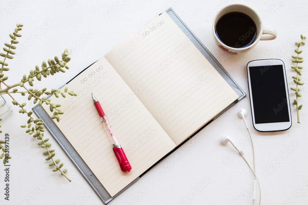 notebook planner ,mobile phone for business work with hot coffee arrangement flat lay style on table white at office desk notebook planner ,mobile phone for business work with hot coffee arrangement flat lay style on table white at office desk