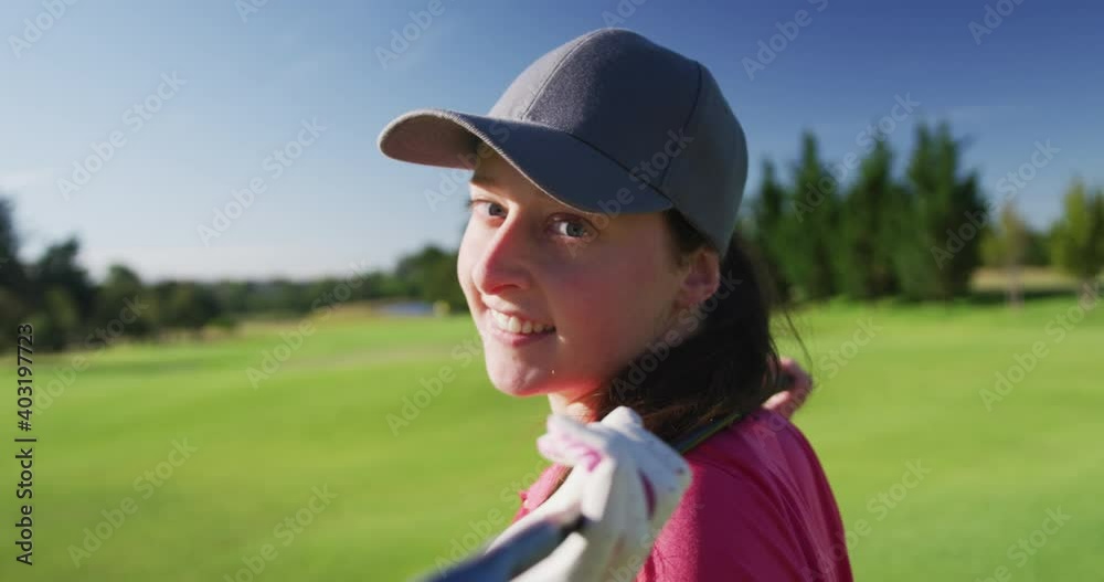 Portrait of female golf player smiling with gold club on her back on golf course Portrait of female golf player smiling with gold club on her back on golf course