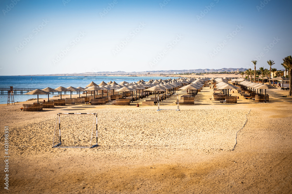 Summer beach with empty sunbeds and umbrellas. Warm summer morning on the egyptian beach Summer beach with empty sunbeds and umbrellas. Warm summer morning on the egyptian beach