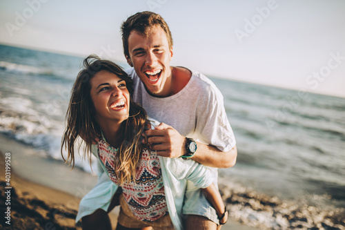 Young woman giving piggyback ride to boyfriend on beach. photo