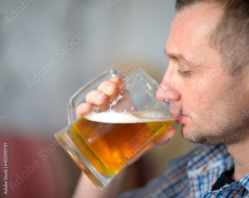 The man is drinking a fresh, cold alcoholic beer from a large mug