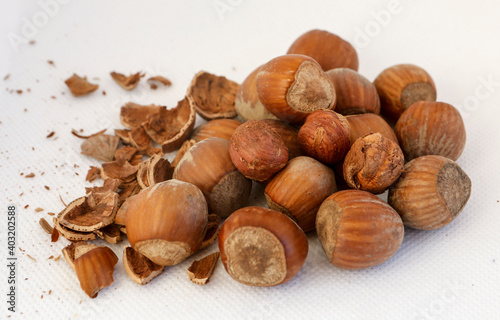 Hazelnuts, some of them shelled, on a white background.