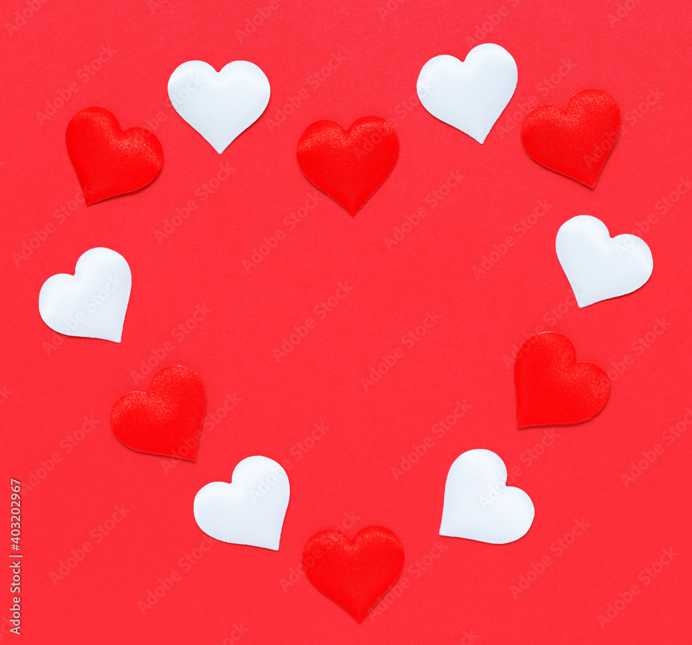 Decorative small red and white hearts are laid out in the shape of a large heart on a red background.
