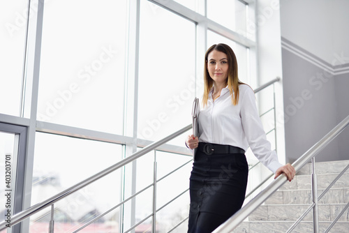 Portrait of a woman with documents in hands on the background of a large window and stairs