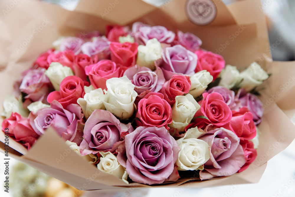 Delicate bouquet of multi-colored roses in craft paper.