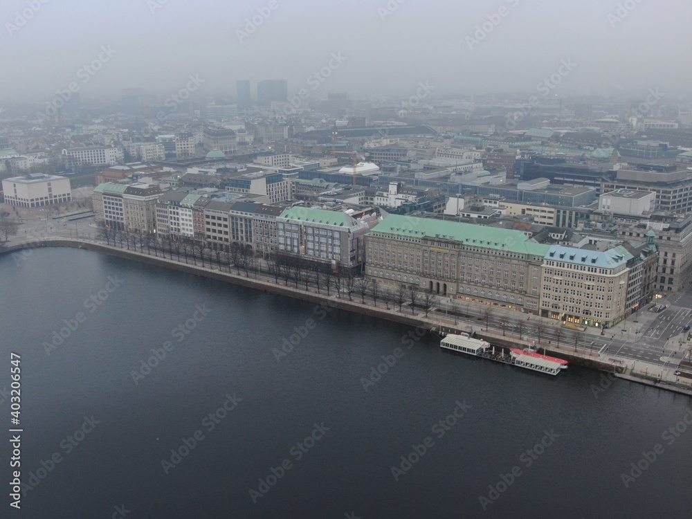Cityscape of Central Hamburg as seen from the river side of the inner alster in a misty atmosphere