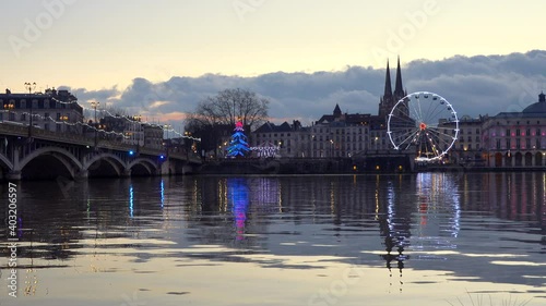 The Ferris wheel, two carousels and the cathedral reflecting on the river Adour at sunset in Bayonne, France