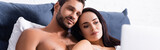 smiling sexy couple looking at blurred laptop on foreground in bedroom, banner