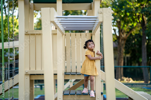 Cute little girl in yellow dress playing at playground.