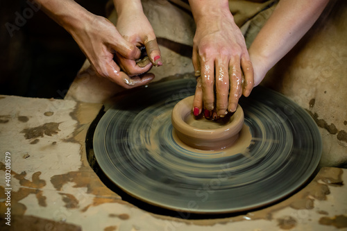 Pottery classes, student making clay pot on wheel. Close-up of dirty hands, sculpting clay crockery pottery training