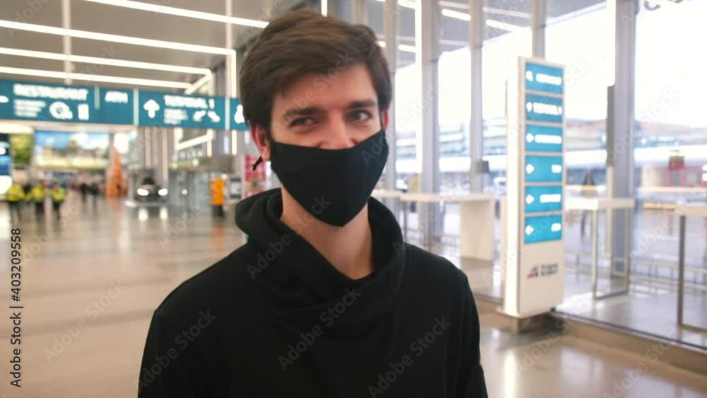 A man in a black mask speaks a video review. Oral communication using journalism. He looks into the camera speaks. Respect the mask in an obscure place. In the background the airport lobby. A man in a black mask speaks a video review. Oral communication using journalism. He looks into the camera speaks. Respect the mask in an obscure place. In the background the airport lobby.