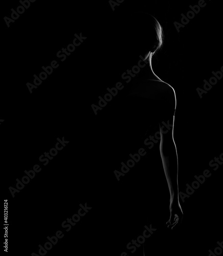 Black and white silhouette of a beautiful woman seen one half of the body on a dark background.