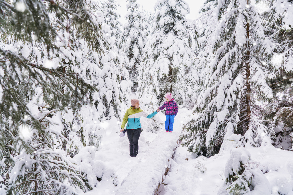 mother and daughter go for a walk in the beautiful snowy forest