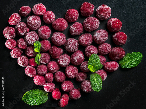 frozen raspberries laid out in the shape of a heart on a dark background. Frozen raspberry heart