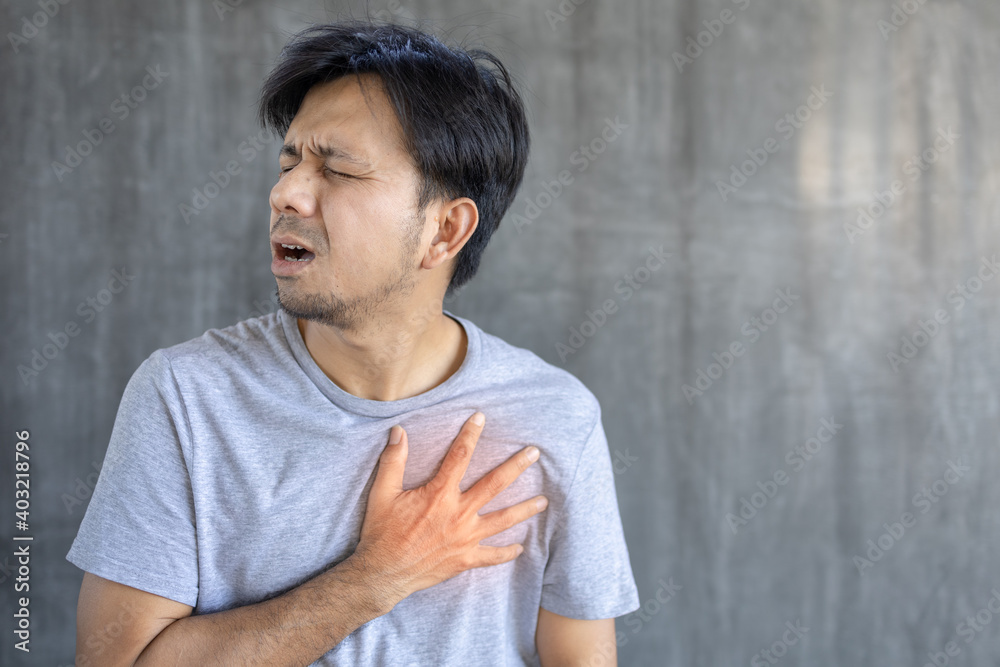 Chest pain, young asian man having heart attack, man suffering from heartache over gray background, healthcare concept Chest pain, young asian man having heart attack, man suffering from heartache over gray background, healthcare concept