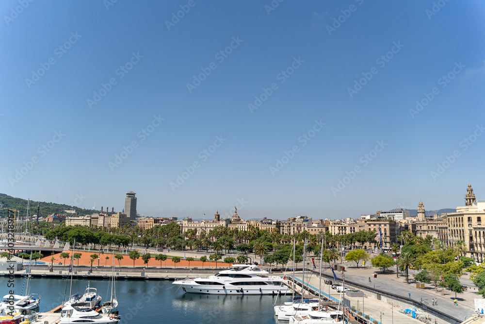 Many white yachts are moored in the port of Barcelona on a sunny summer day