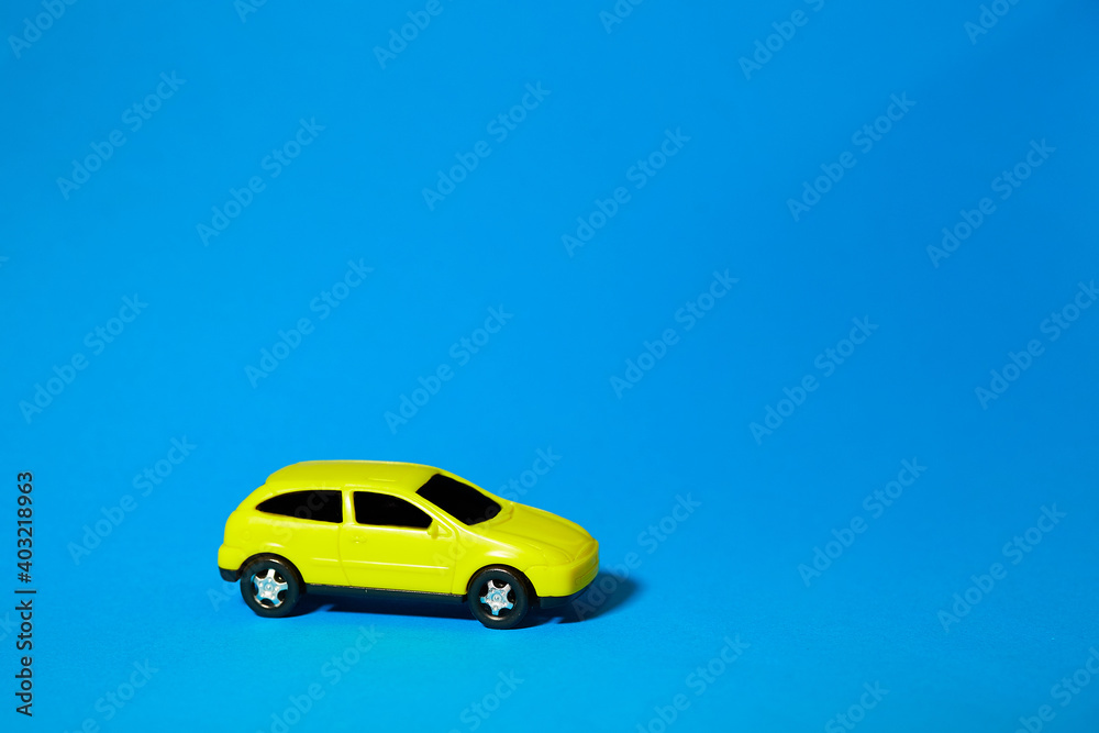 yellow toy car on blue background, concept idea of taxi and cargo delivery during quarantine