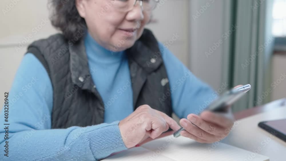 Senior asian woman wear glasses and sweater using smartphone, sit down stay warm at home living room in the cold winter, elderly eye sight happy retirement life, modern technology, close up shot Senior asian woman wear glasses and sweater using smartphone, sit down stay warm at home living room in the cold winter, elderly eye sight happy retirement life, modern technology, close up shot