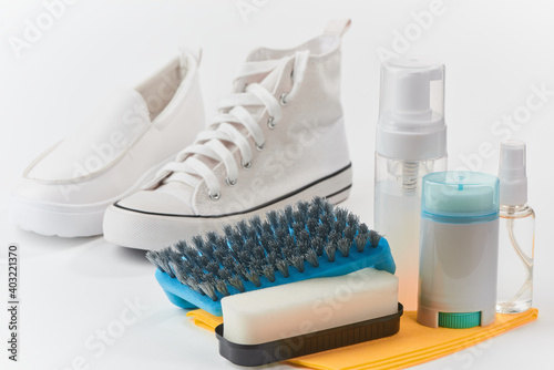 Leather and canvas shoes and cleaning kit on white background