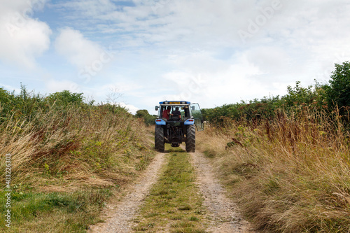 Tractor drives up a country lane between the fields - rural lifestyle concept