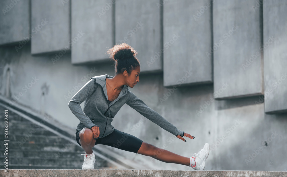 Fototapeta premium Conception of sport. Young african american woman in sportive clothes have workout outdoors at daytime