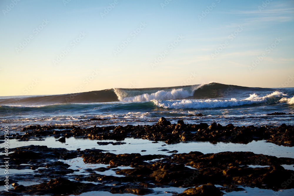 wave breaking over shallow reef during sunrise 