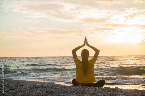 Yoga woman in Lotus position practicing yoga and meditation. outdoors on the evening ocean