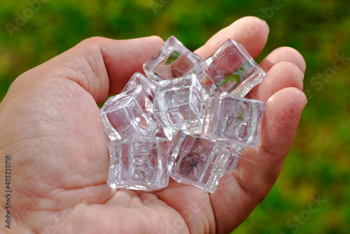 Transparent and cool ice cubes are in strong hands on a blurred background.